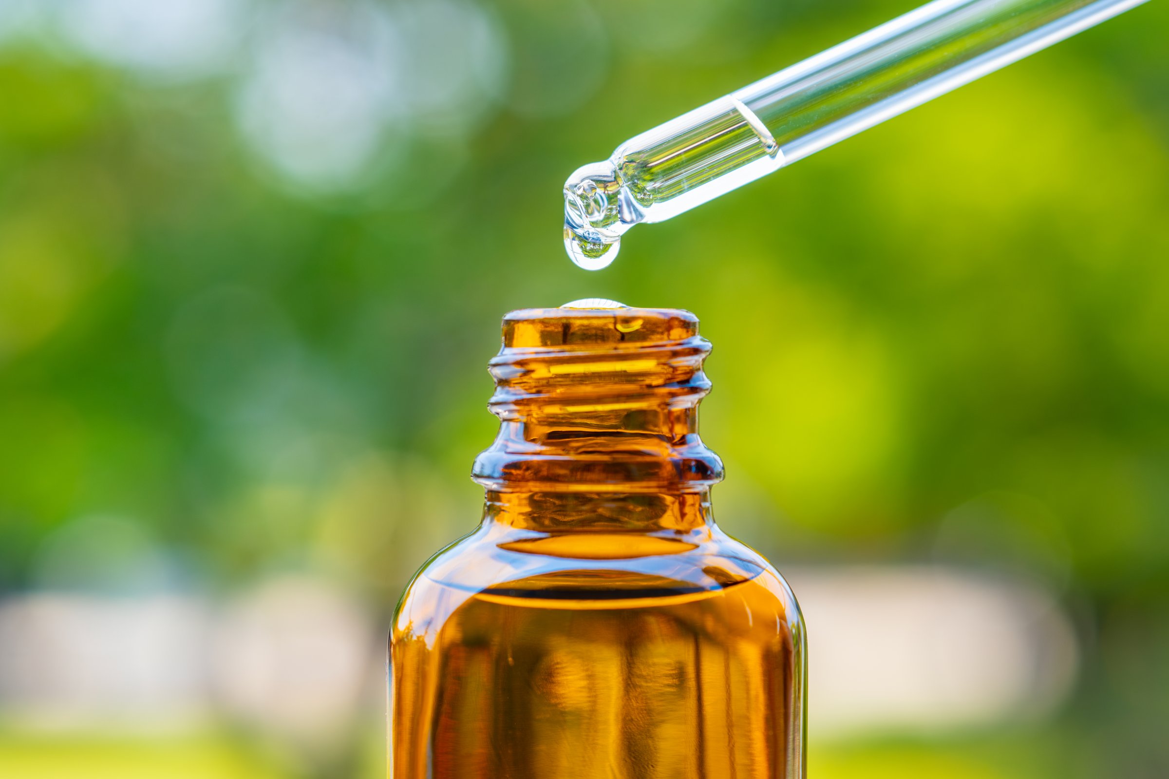 Dropping serum collagen moisturizer of face into clear yellow bottle soft light background. Protector skin Treatment facial essence oil, Vitamin C. Beauty and spa Concept.