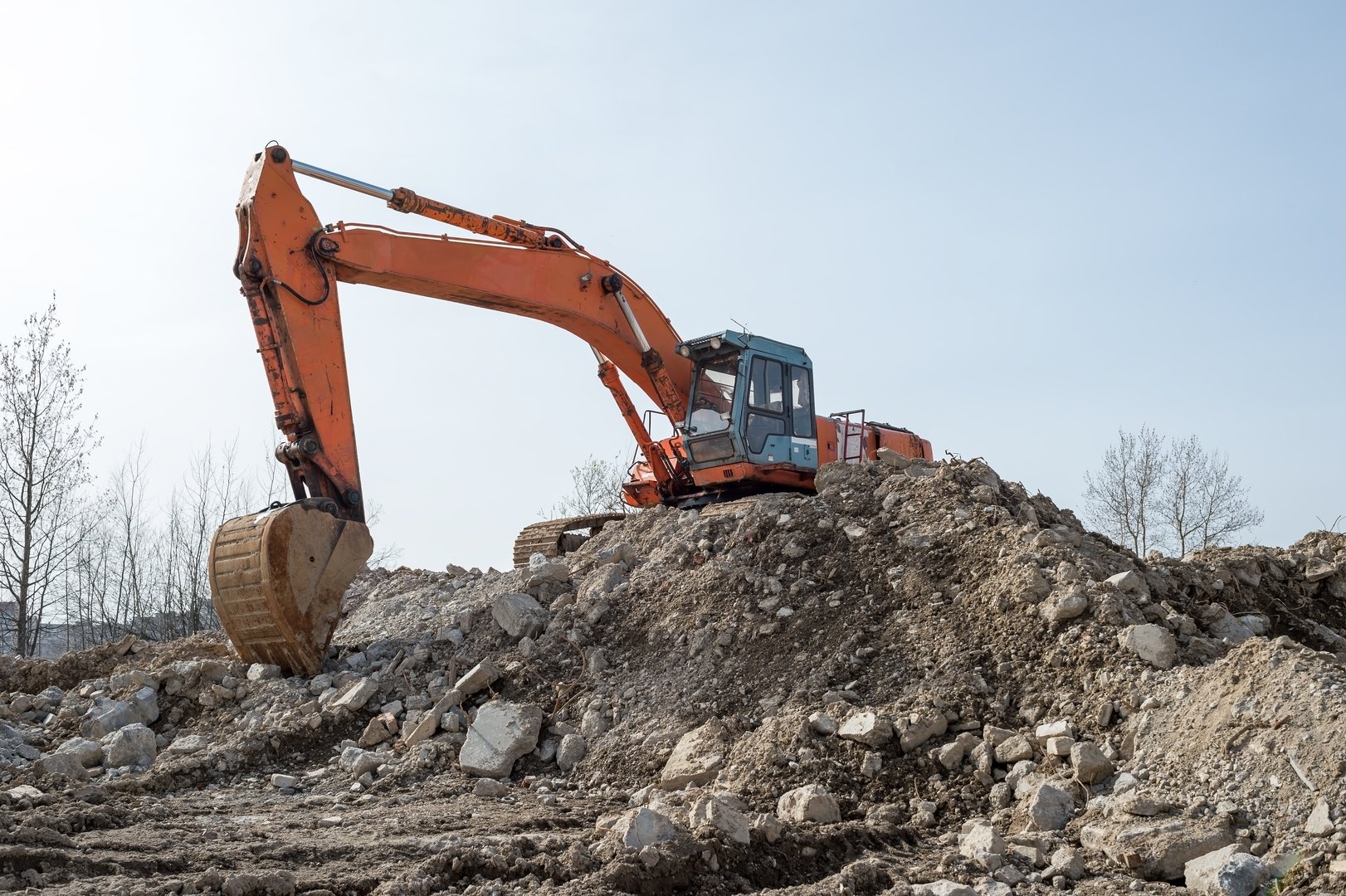 Orange excavator on rubble