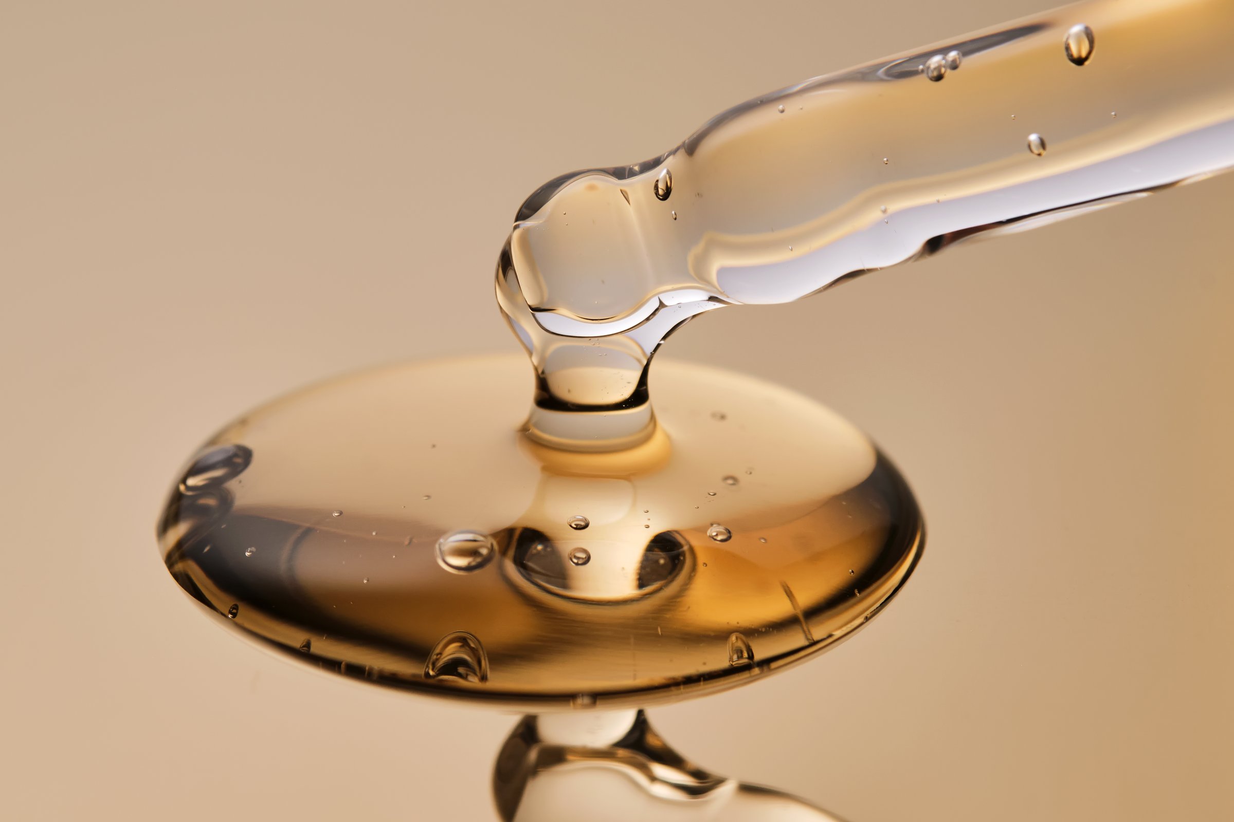 A pipette with a beautiful drop of gel-textured facial serum. High quality photo.