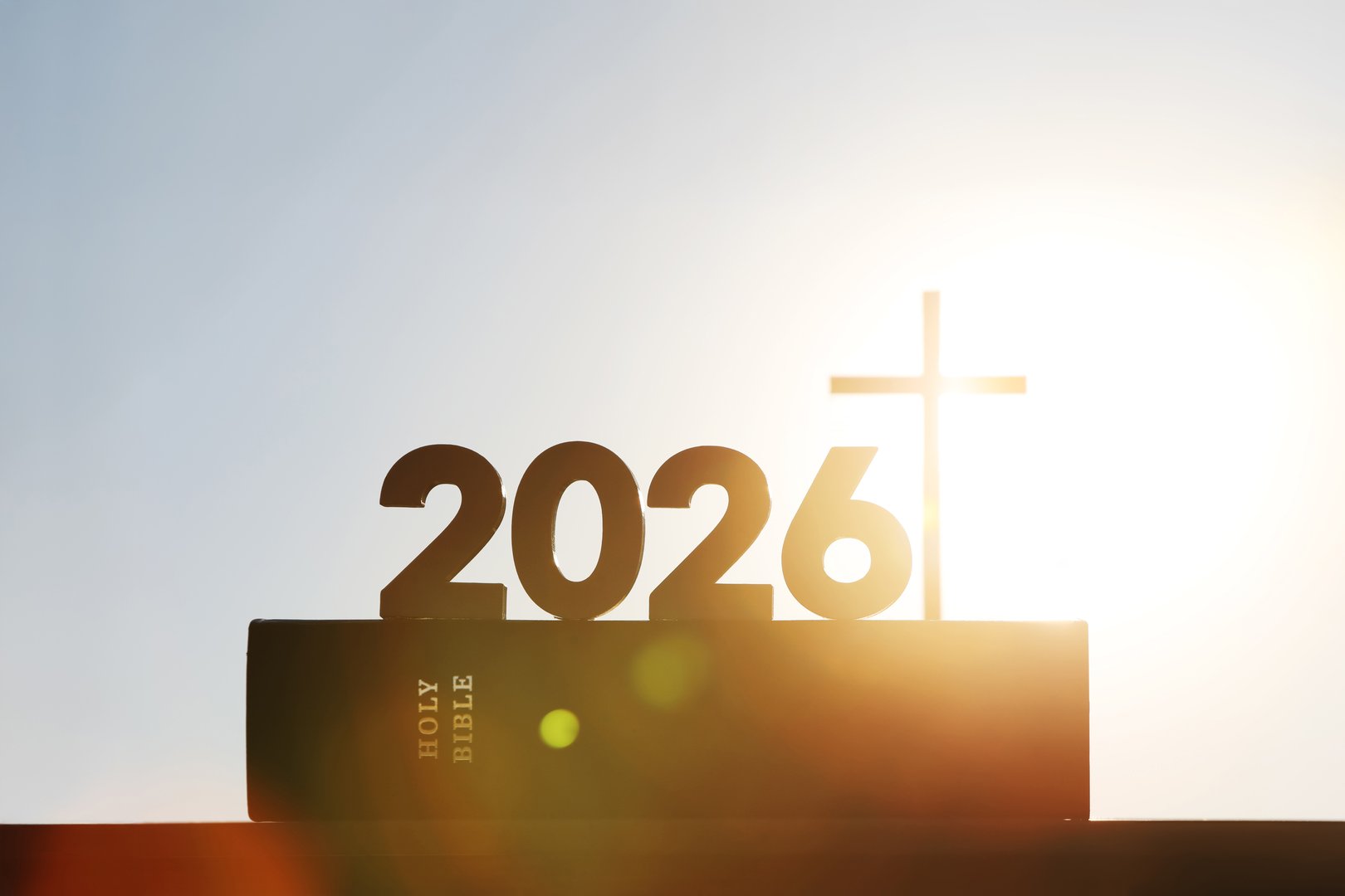 New Year's sunrise in 2026, with the bright rising sun and the Holy Cross of Jesus Christ and the Bible in the background.