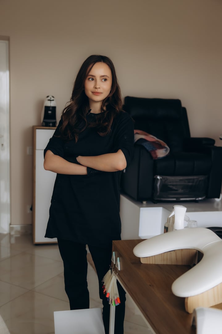 Woman nail technician standing with crossed arms in a beauty salon. Professionalism and beauty care concept