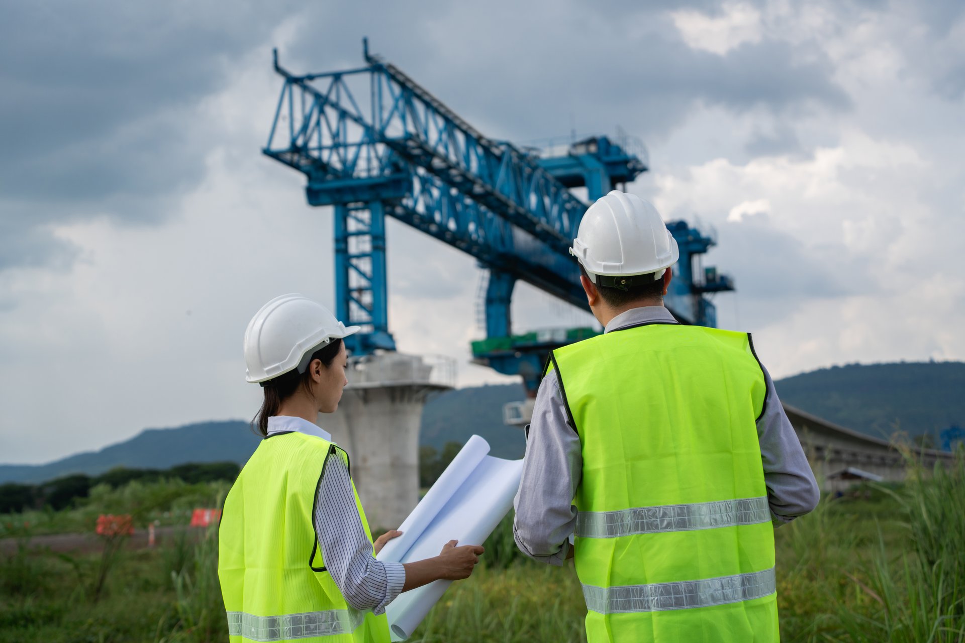 The survey team is using a theodolite and road construction plans. Civil engineers are measuring with surveying tools during the construction.