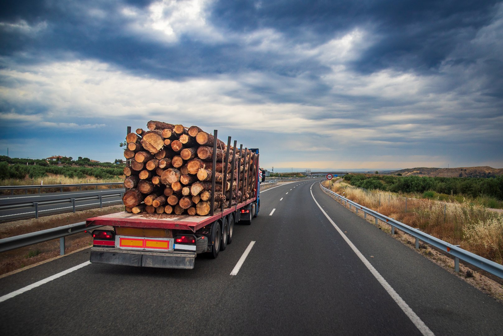 Truck with semi-trailer adapted for transporting logs driving on the highway.