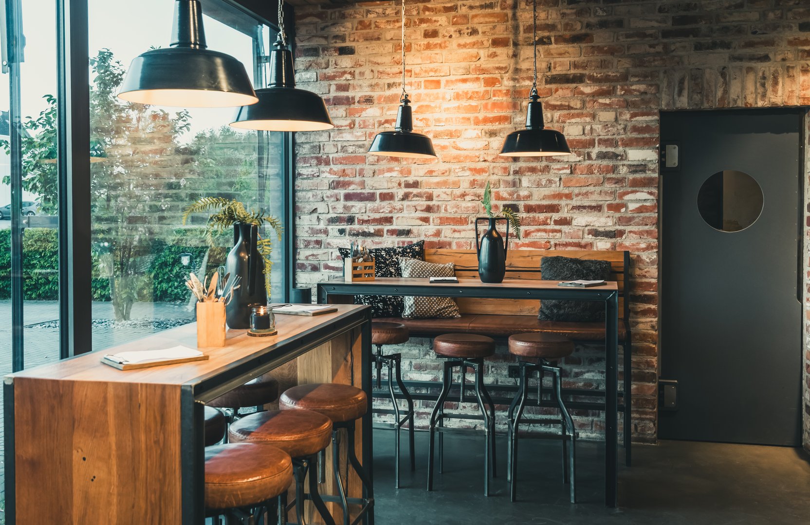 Seating area with bar tables and bar chairs in a modern cafe, industrial style with stone wall, wood and black steel