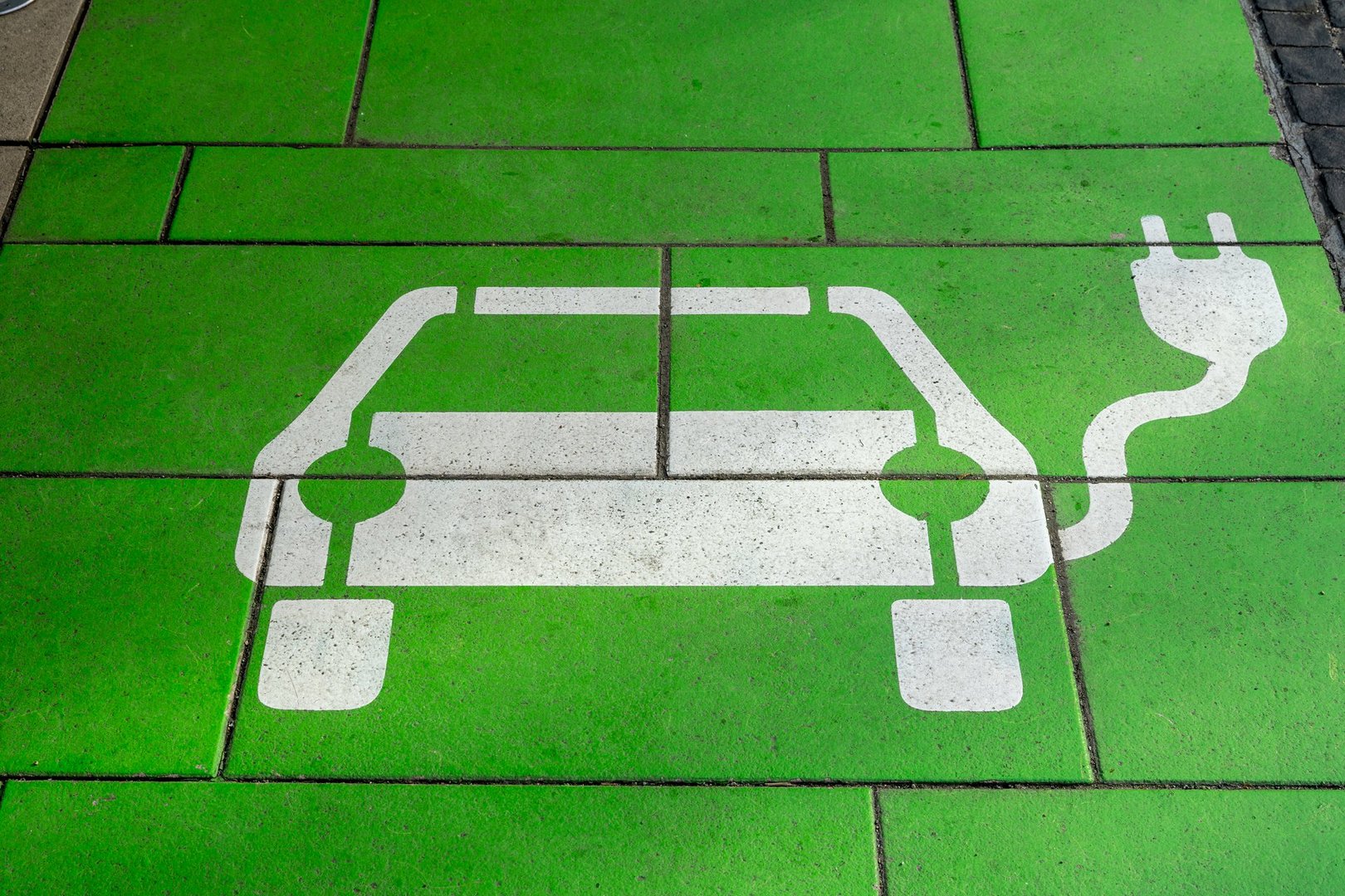 Empty green-painted parking space with a white symbol of an EV