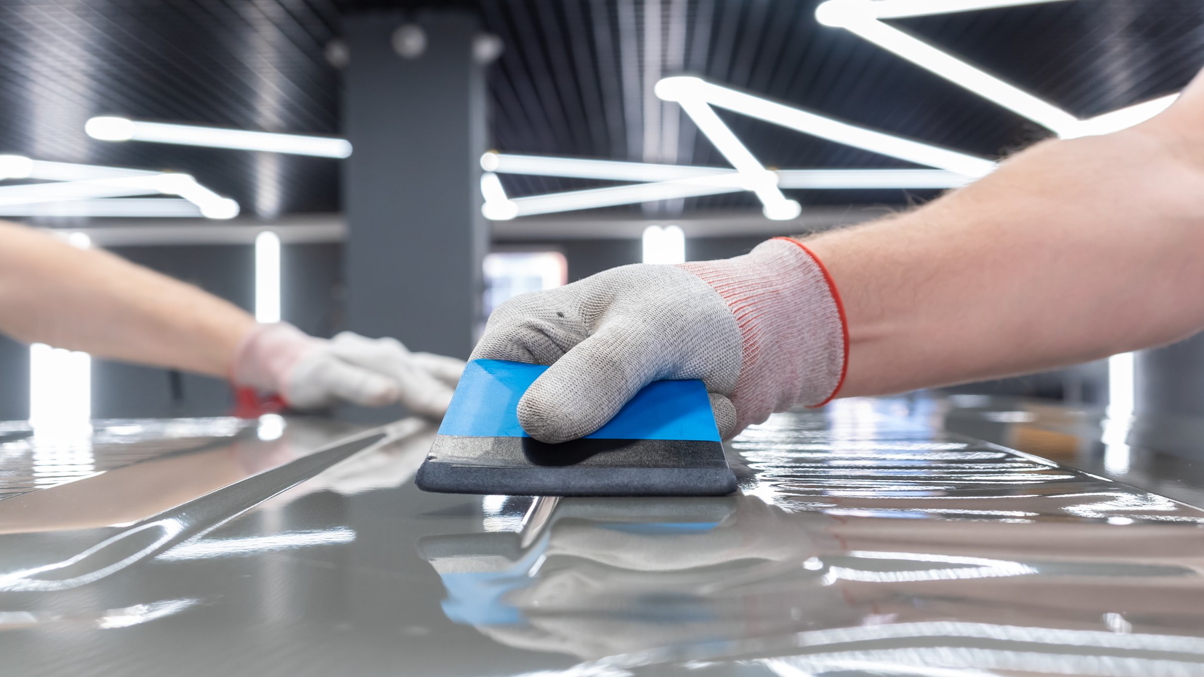 A specialist in wrapping a car with gray matte vinyl or ppf film in the process of work. PPF is a polyurethane, protective film that protects the paint from scratches. Car wrapping, tuning, styling.