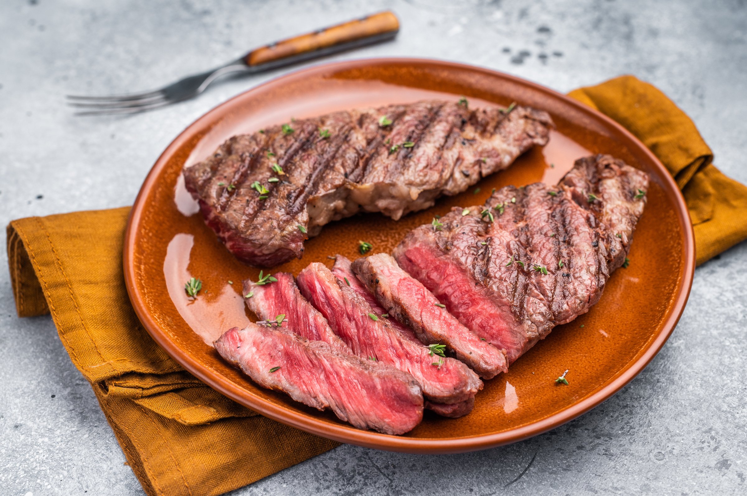Tender flat iron steak, grilled to enhance its natural flavors and tenderness. grey background. top view.