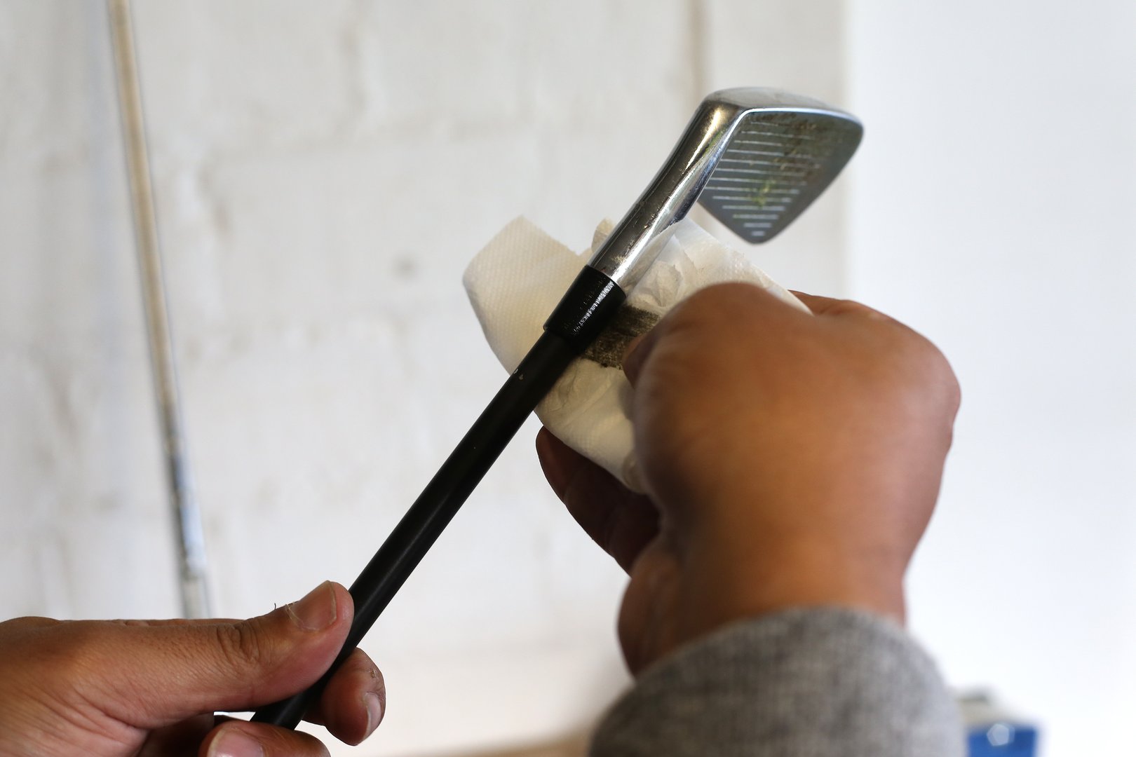 A close-up view of Golf Club Builder cleaning the ferrule (plastic part) on the golf club.