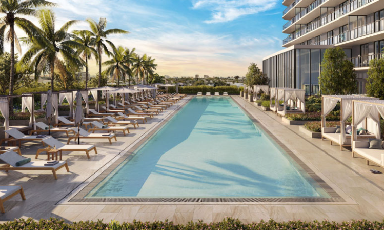 Modern outdoor pool with lounge chairs, cabanas, palm trees, and a tall building in the background under a blue sky.