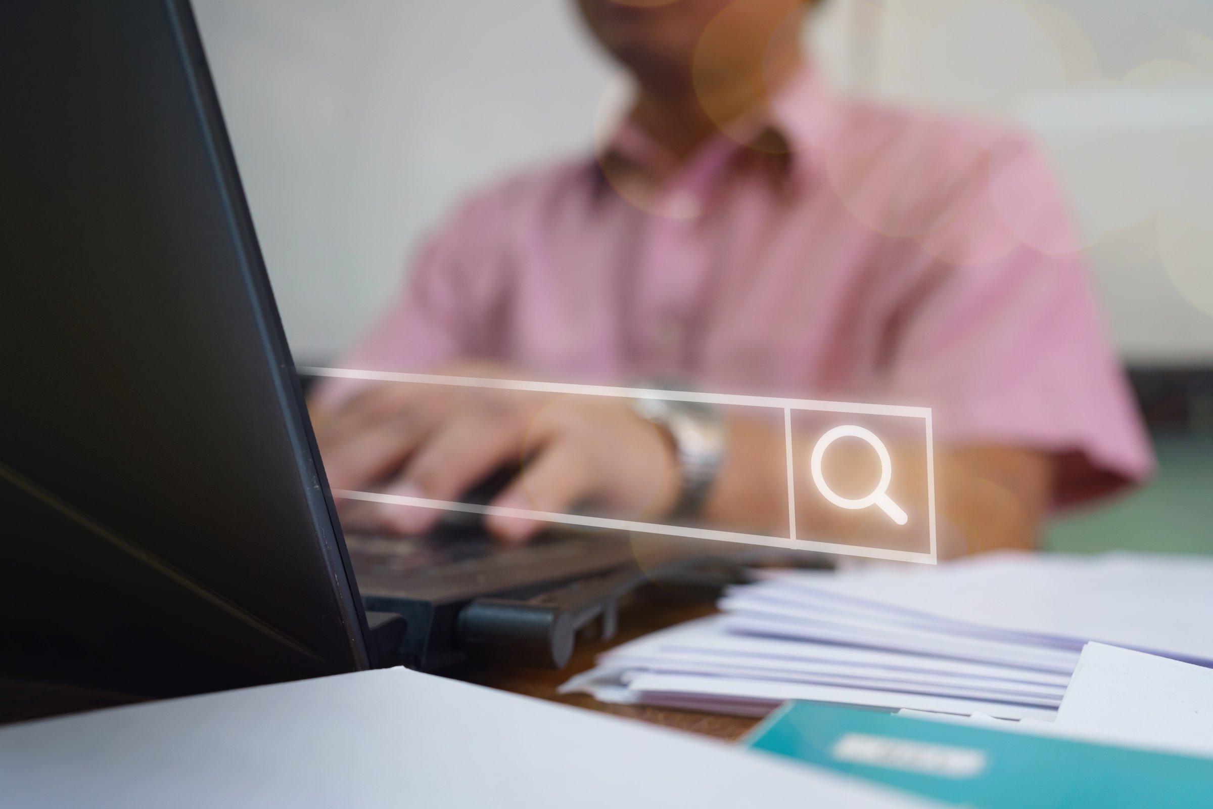Office worker using a laptop with a glowing search bar interface, symbolizing online research, information retrieval, and modern digital technology for work and study purposes.