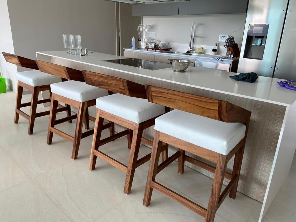 Bancos altos de parota con patas en A, respaldo bajo tipo sling y asiento tapizado claro