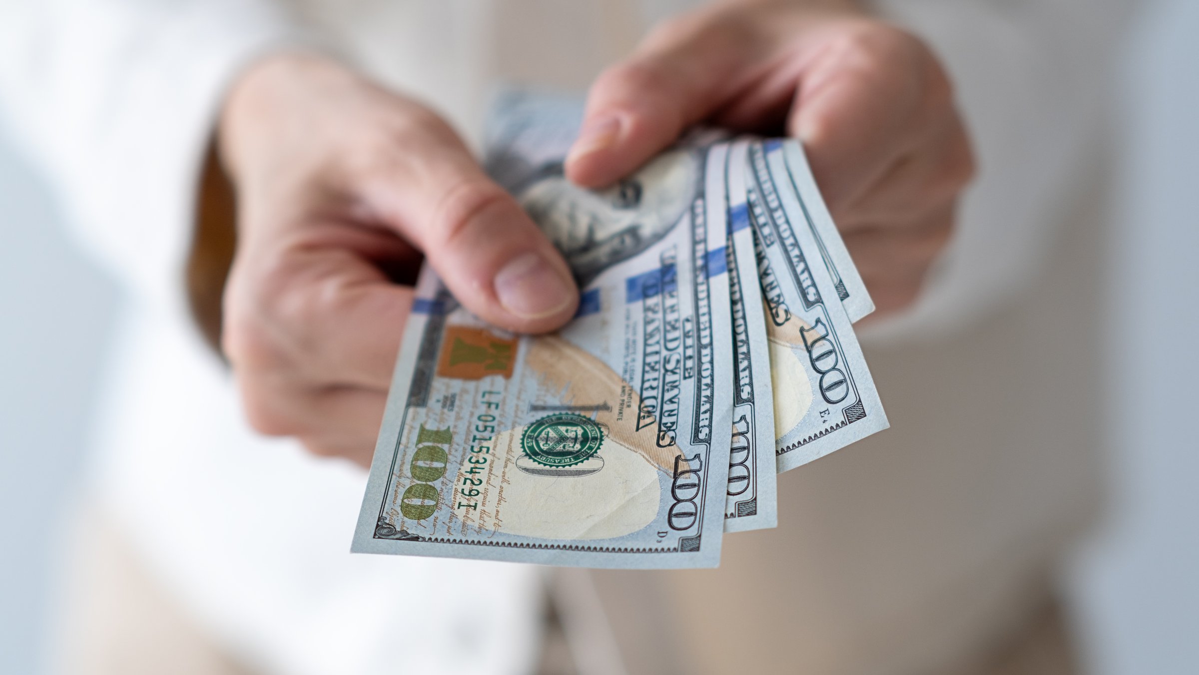 US dollars in wrinkled hands of elderly woman. Concept of pension payments, savings at retirement, pensioner with money