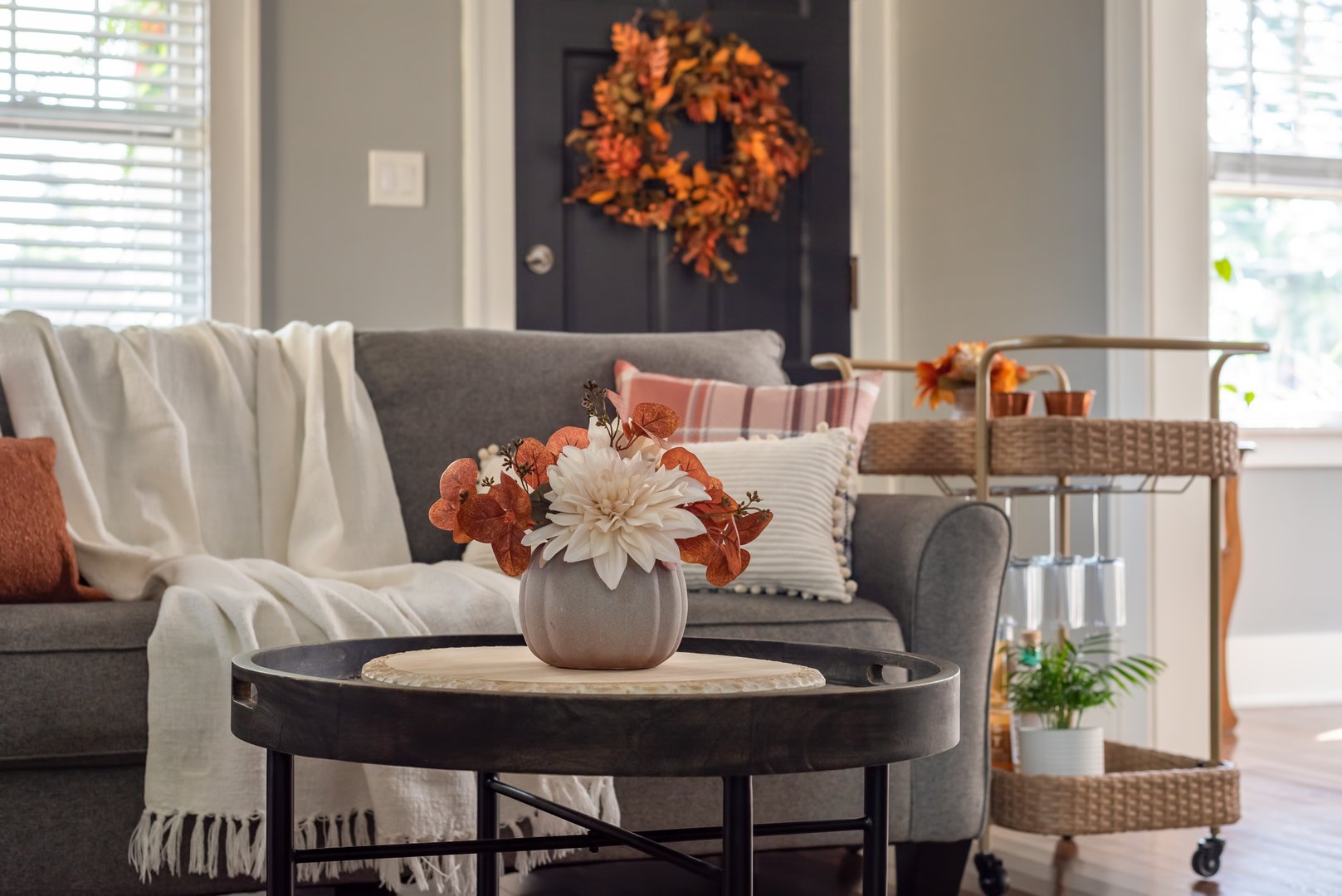 Fall decor in a light and bright living room with a bar car