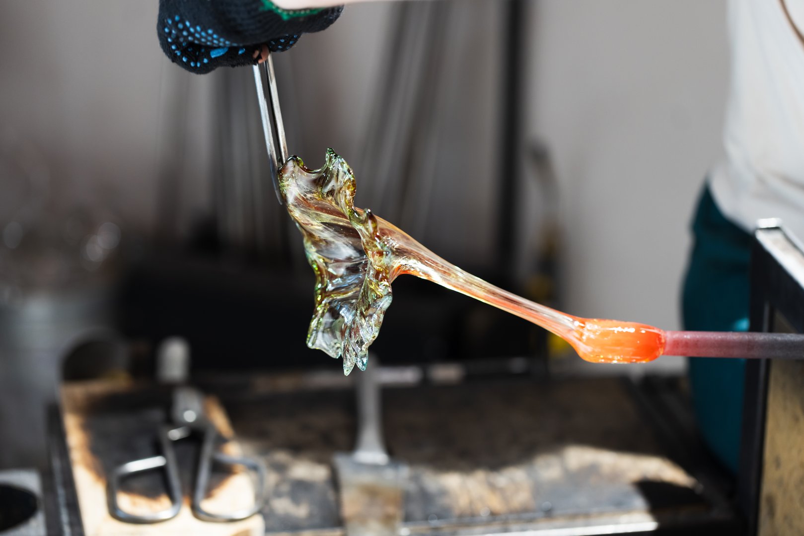 Sculpting flower of molten glass at glass blowing workshop