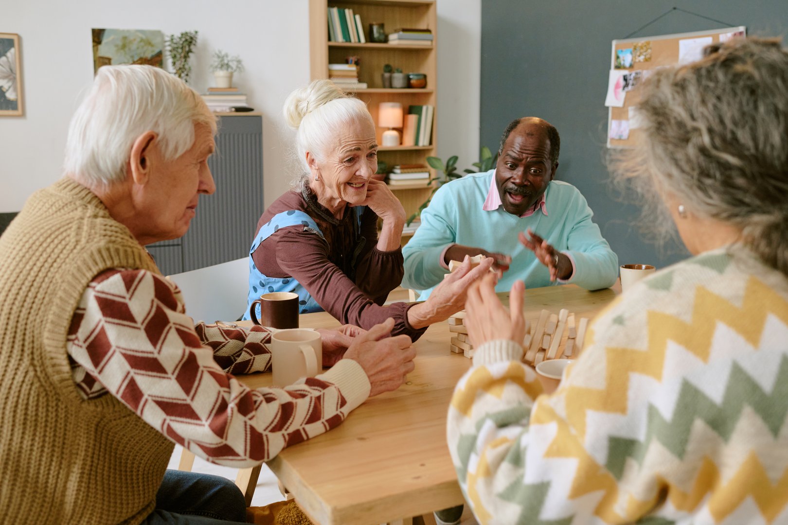 Over shoulder view of biracial companions sitting at table screaming happily while looking at falling tower