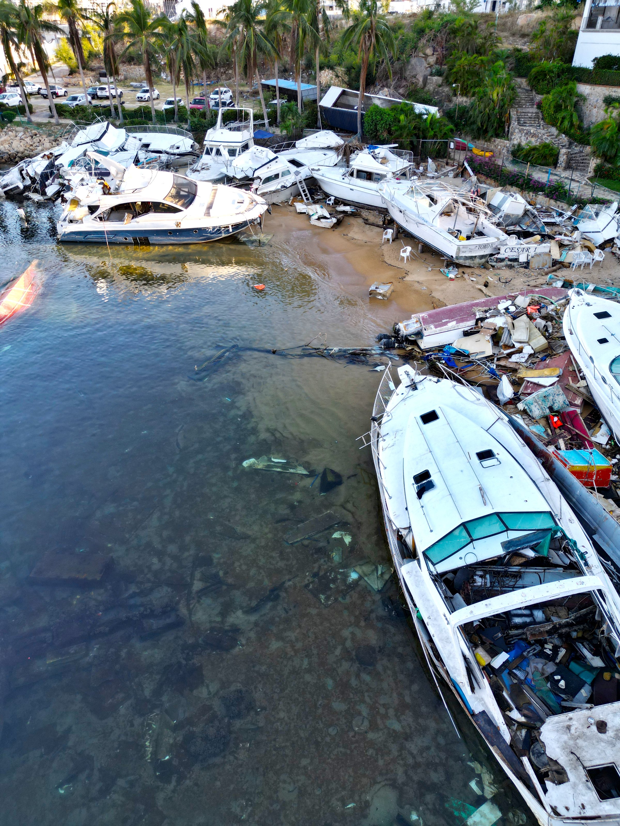 Vertical aerial snapshot capturing the aftermath of Hurricane Otis at the yacht club, revealing sunken and shattered vessels