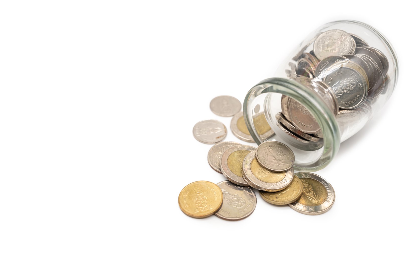 Thai Baht Coins spilled out of jar glass isolated on white background