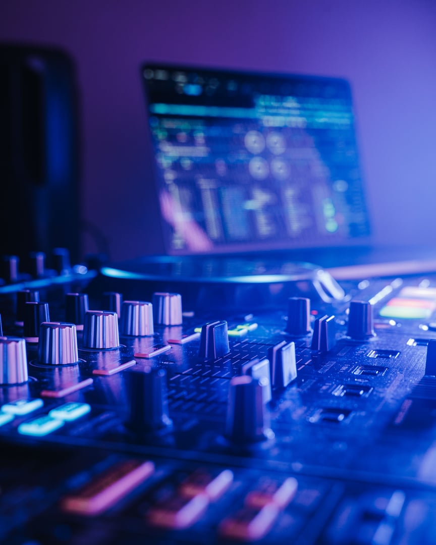 A professional audio mixing board connected to a laptop, displaying the various knobs and buttons.