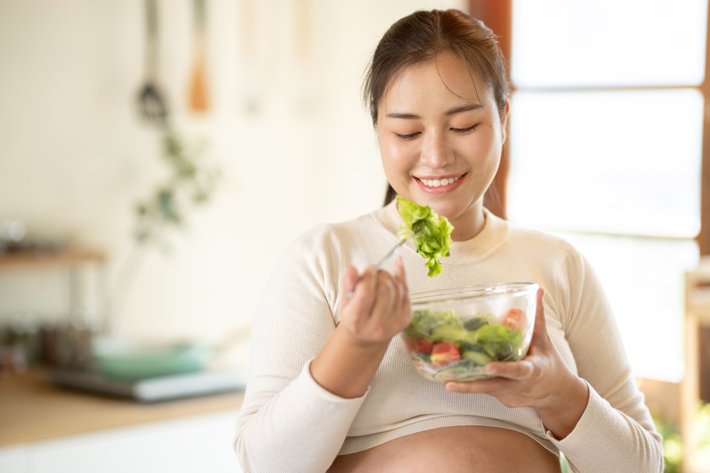 Pregnant Asian woman cooking healthy food at home