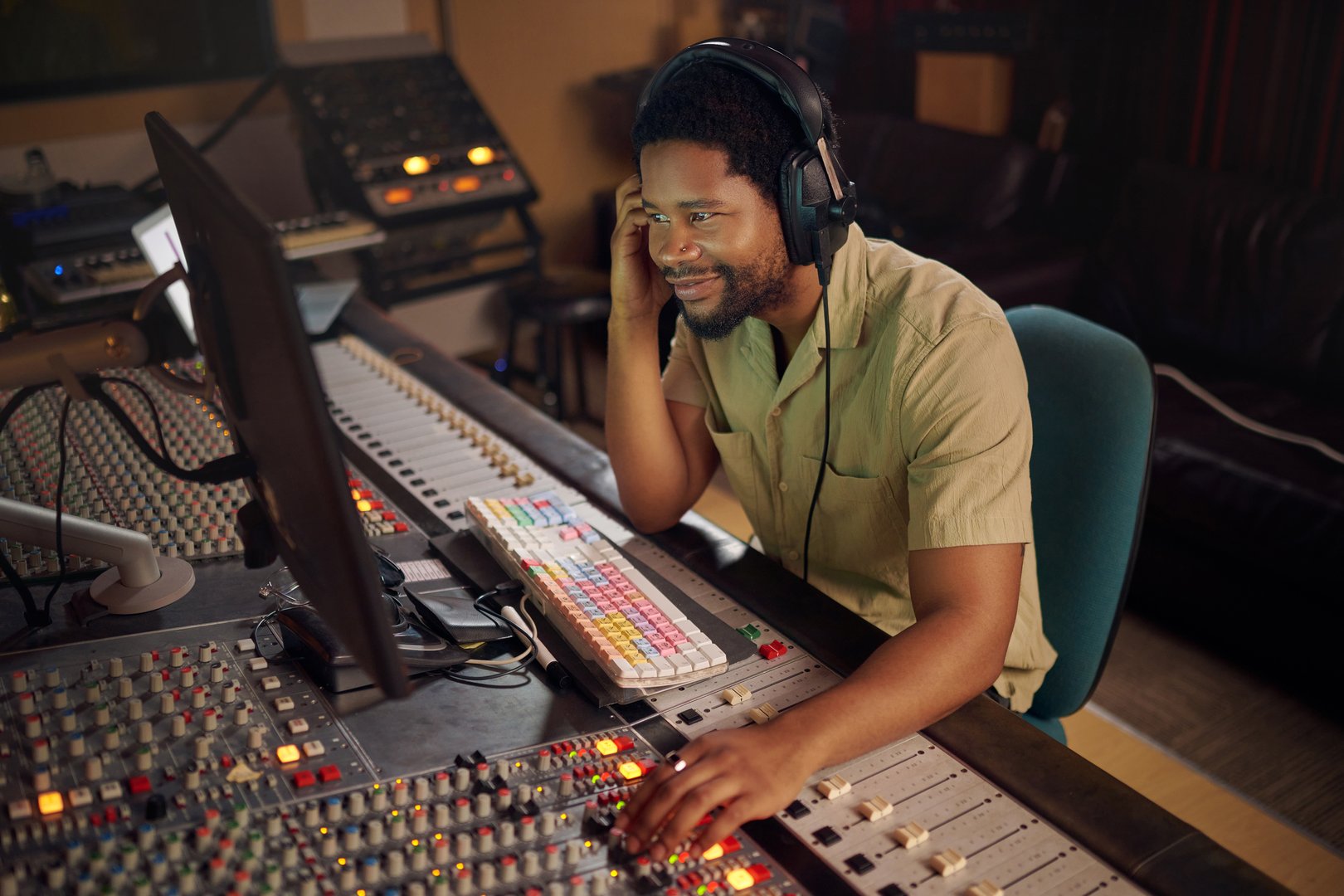 Computer, music and male producer in studio working on a album, song or audio with tech equipment. Happy, smile and black man radio presenter playing a playlist with technology in creative workplace.