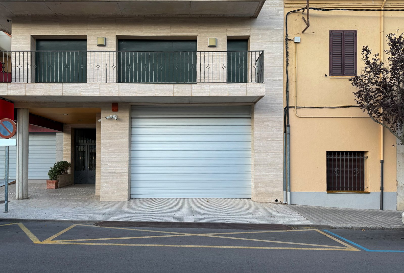 Closed metal roller shutter on beige travertine stone facade