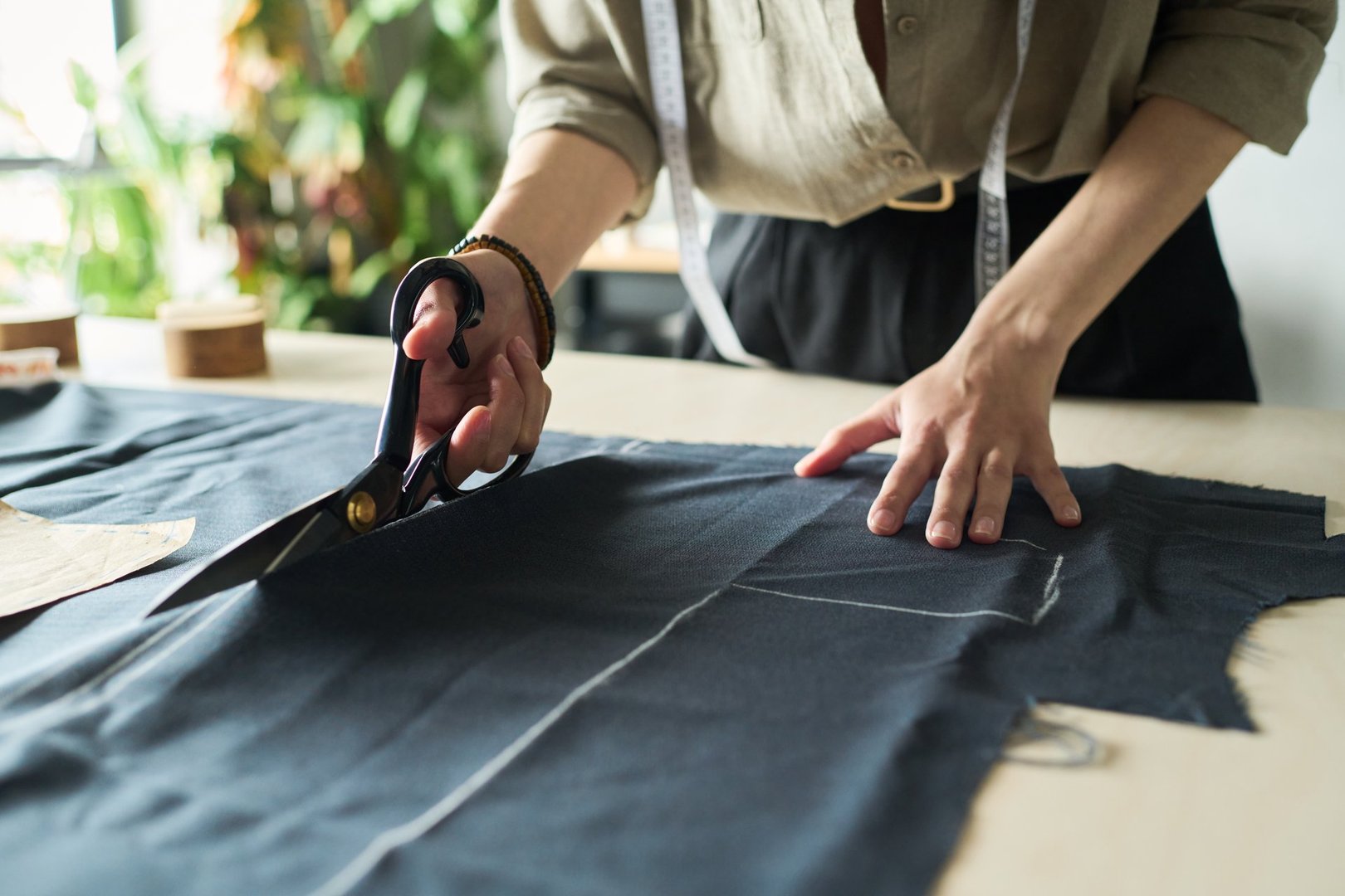 Fashion designer cutting fabric with scissors
