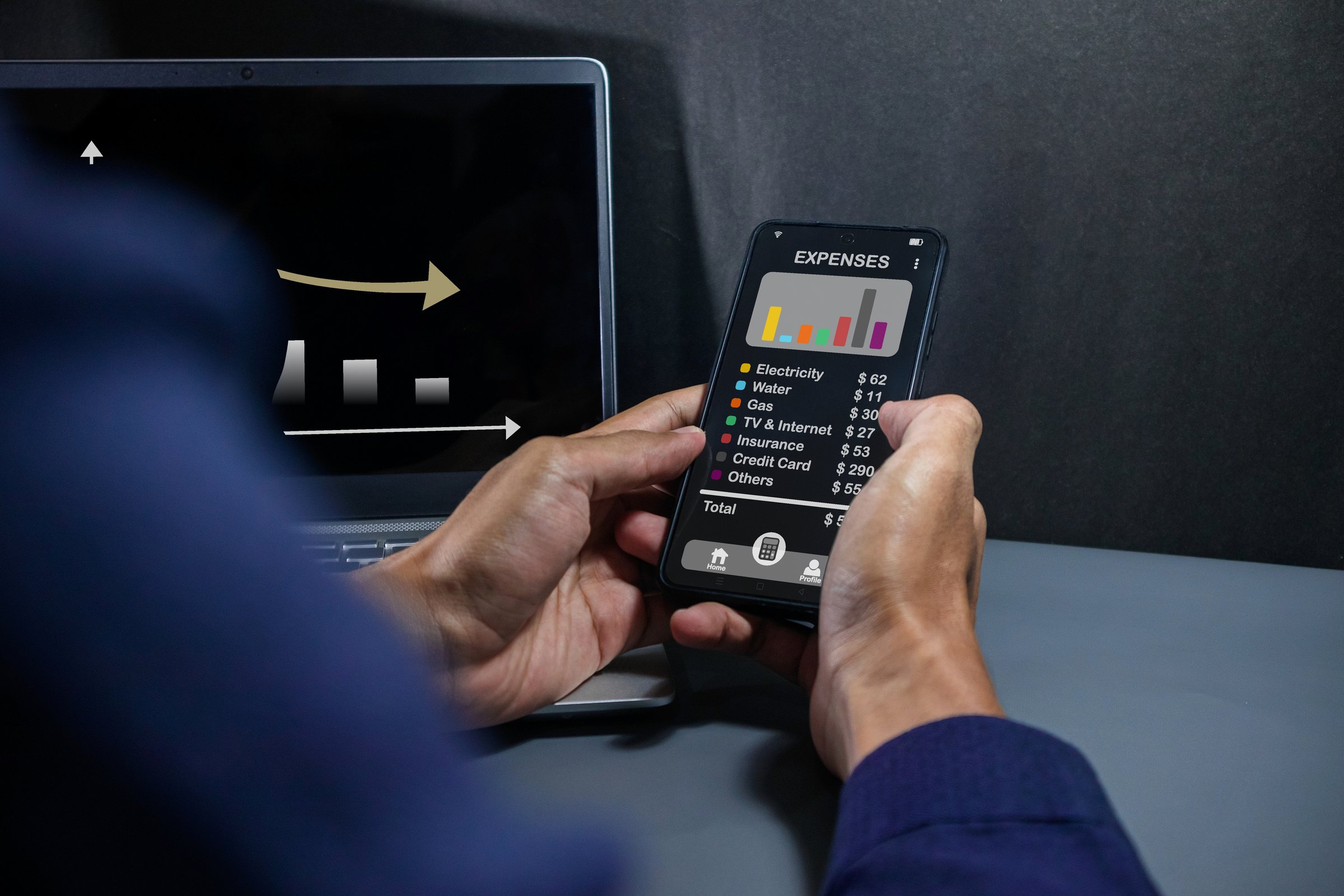 Man using a smartphone app to calculate the monthly bills or household expenses