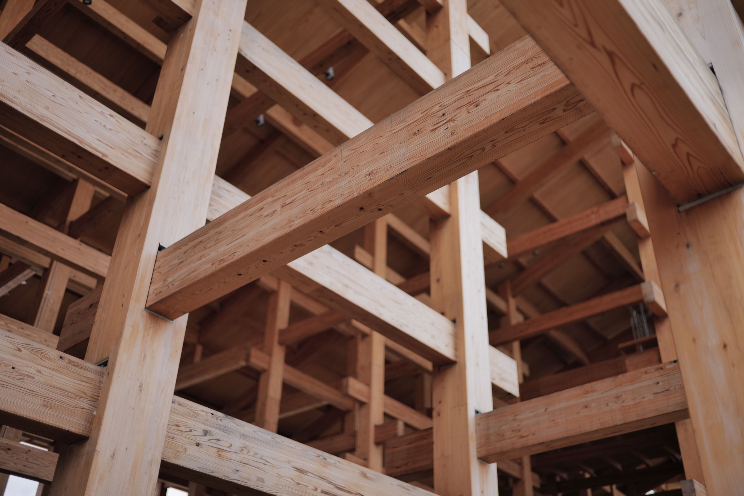 Close-up view of a wooden architectural structure showcasing intricate beams and joints, highlighting craftsmanship and design.