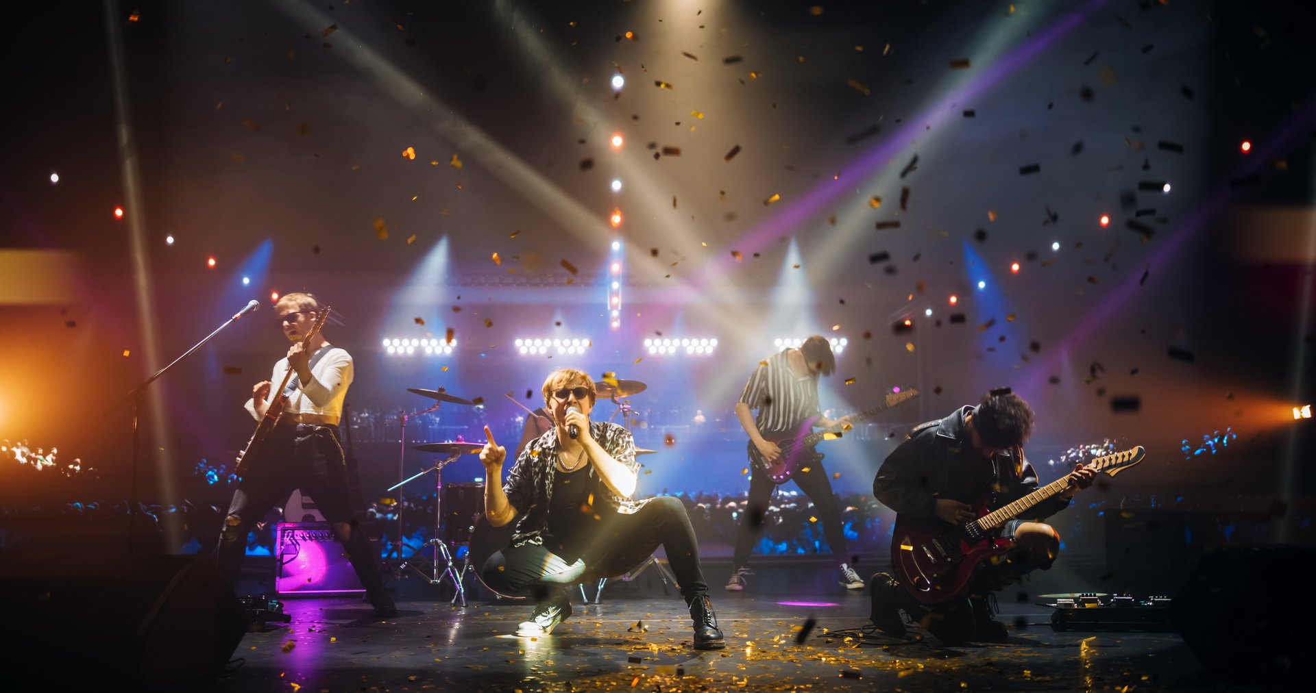 Rock Band Delivers a High-Energy Performance with Lead Guitarist Singing and Playing Electric Guitar in Sunglasses. Vocalist Passionately Singing, Drummer and Bassist Maintaining a Strong Beat