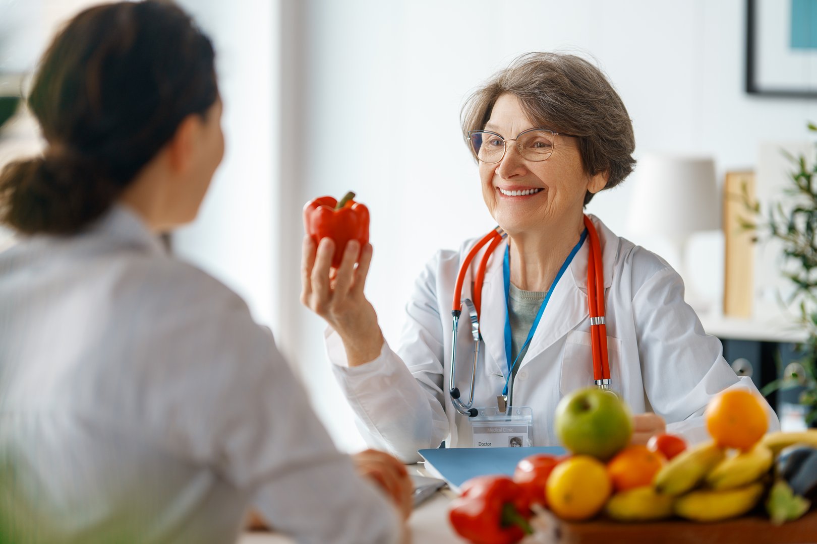 Happy doctor is working in medicine office. A woman is talking to a patient about the importance of eating fruits and vegetables.