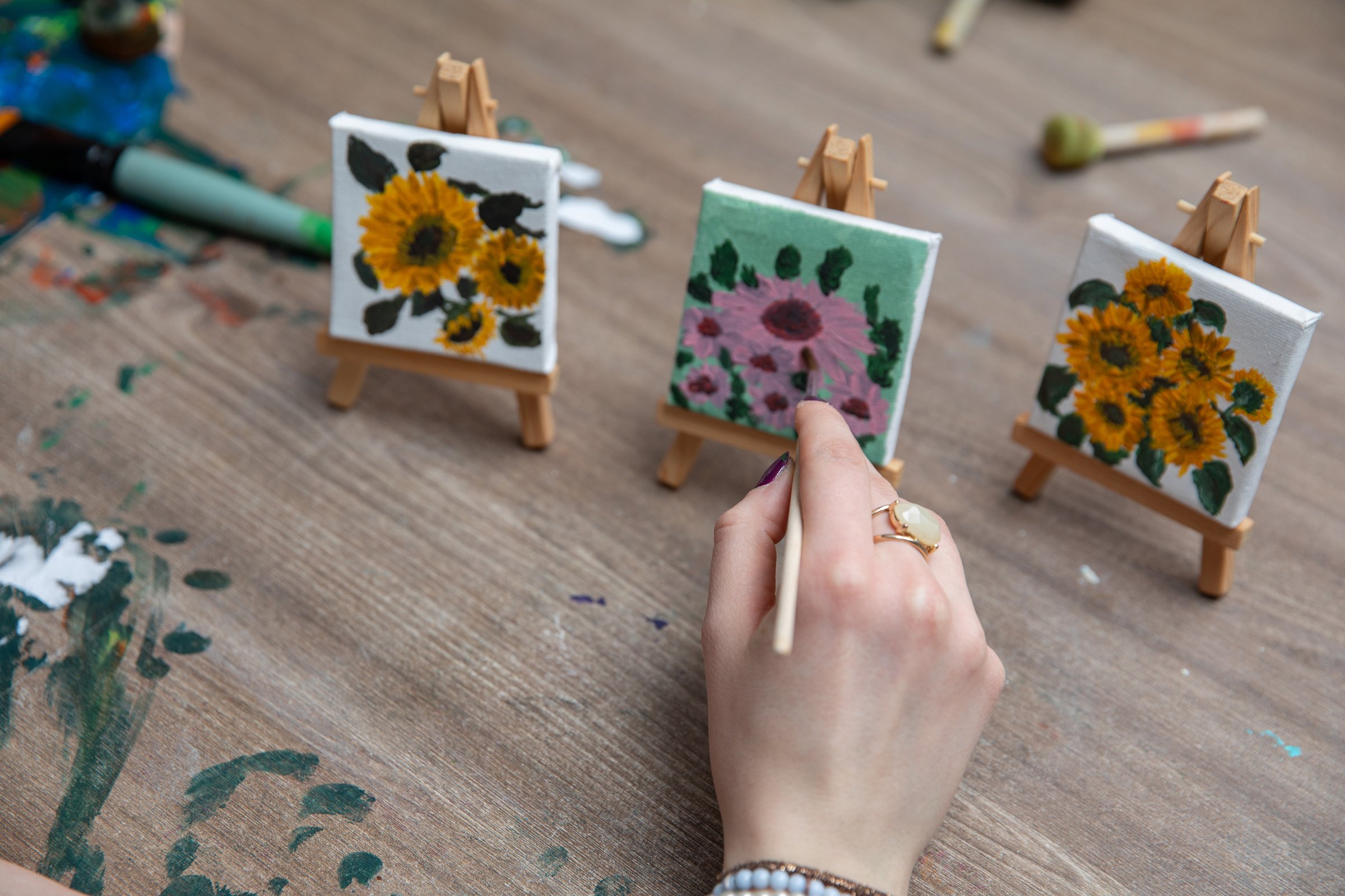 A beautifully handpainted artwork on small canvases, displaying vibrant floral designs on artist easels