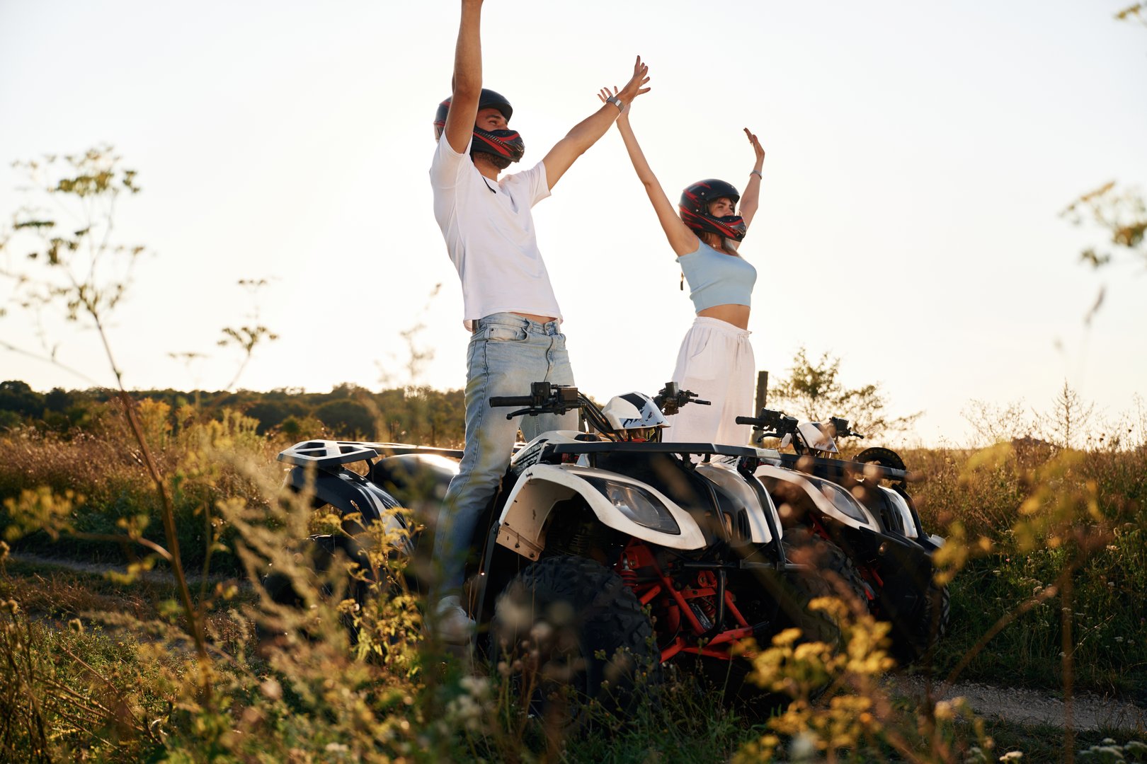 Hands raised up. Man and woman are on ATV outdoors.