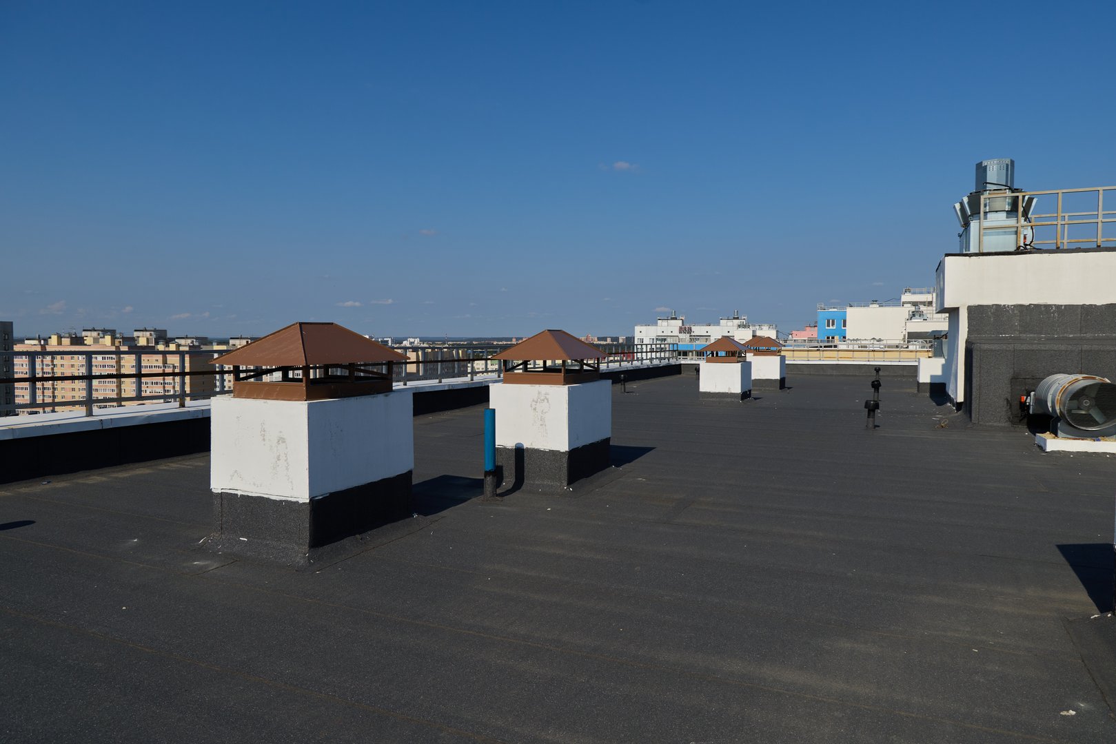 The breathtaking rooftop view features charming chimneys against a vast blue sky in an urban setting