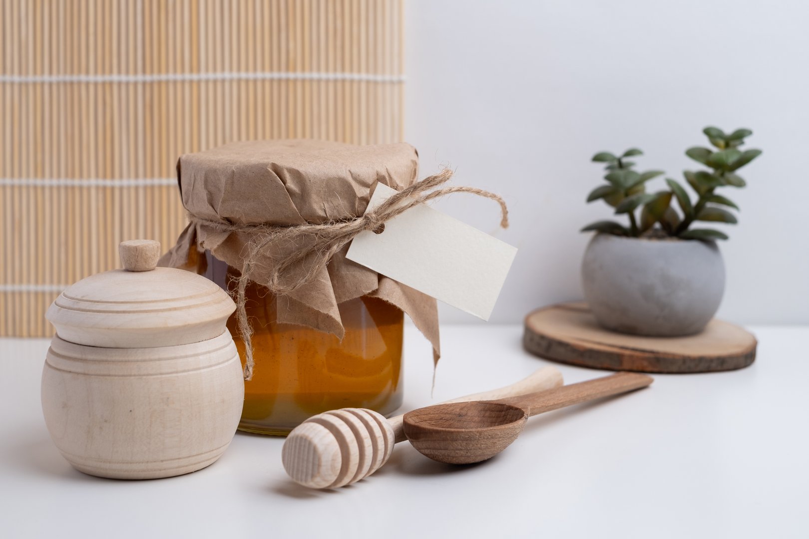 Jar of honey with wooden honey dipper on white kitchen background. Tasty honey bunker.