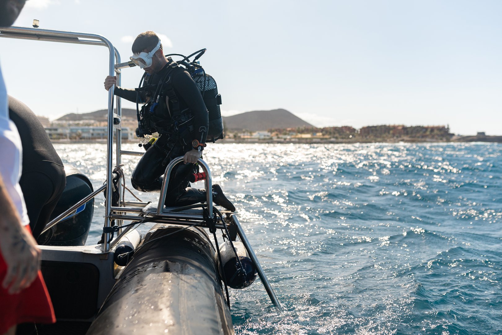 Scuba diver climbing ladder out of ocean after dive
