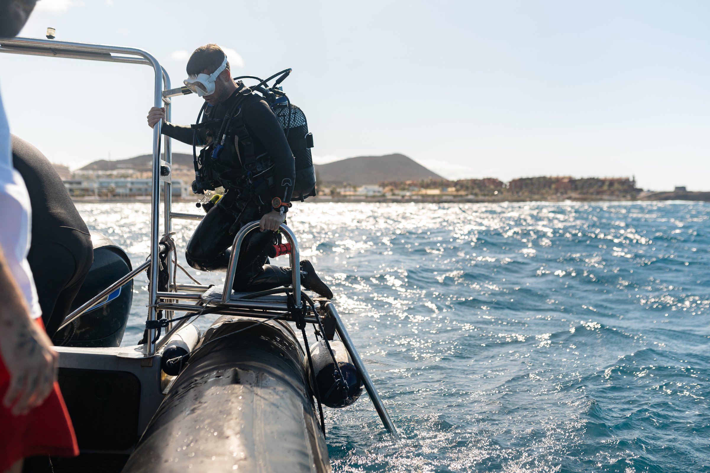 Scuba diver climbing ladder out of ocean after dive on the boat