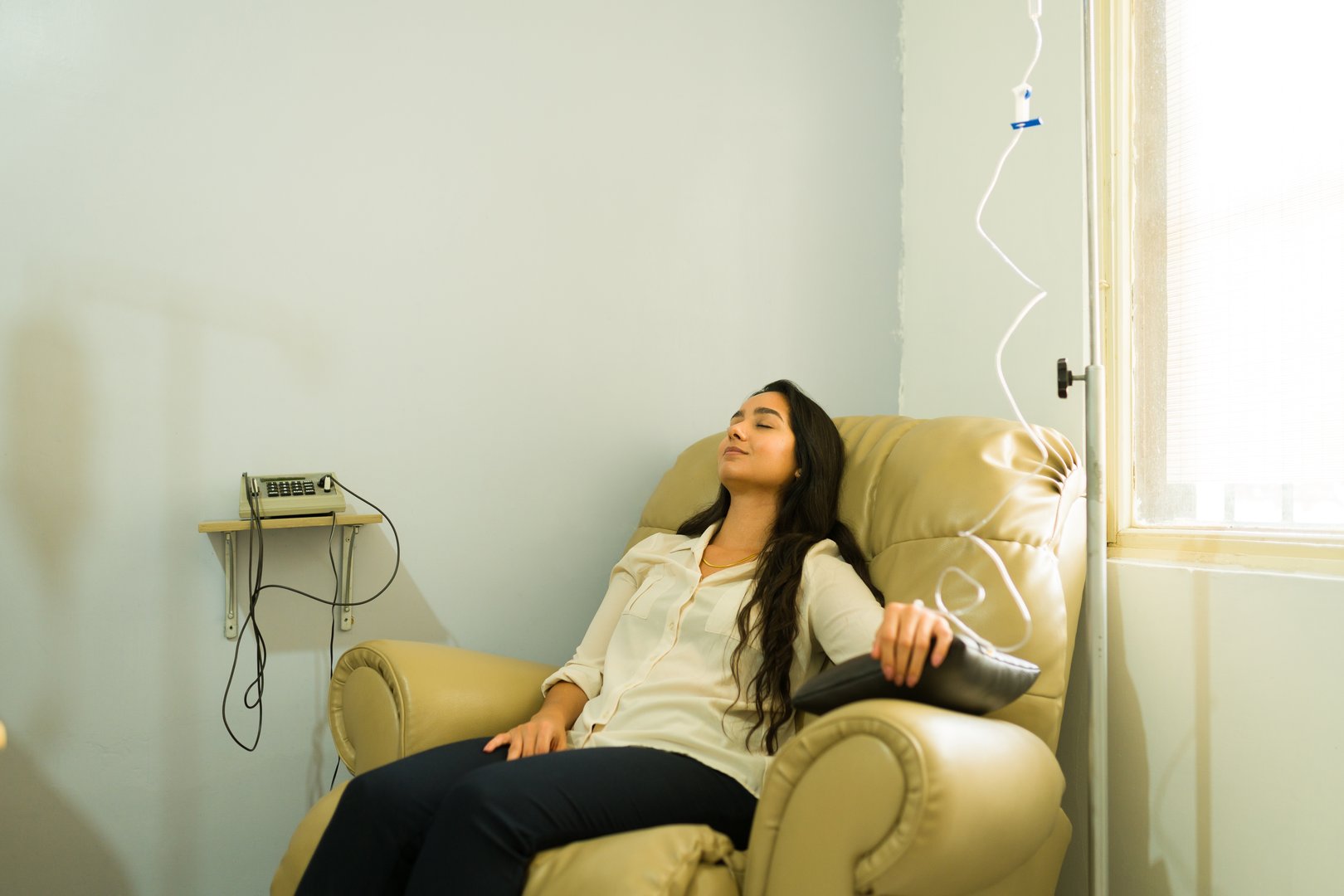 Happy attractive woman relaxing while getting IV drip and vitamin minerals therapy for a better health with a myers cocktail