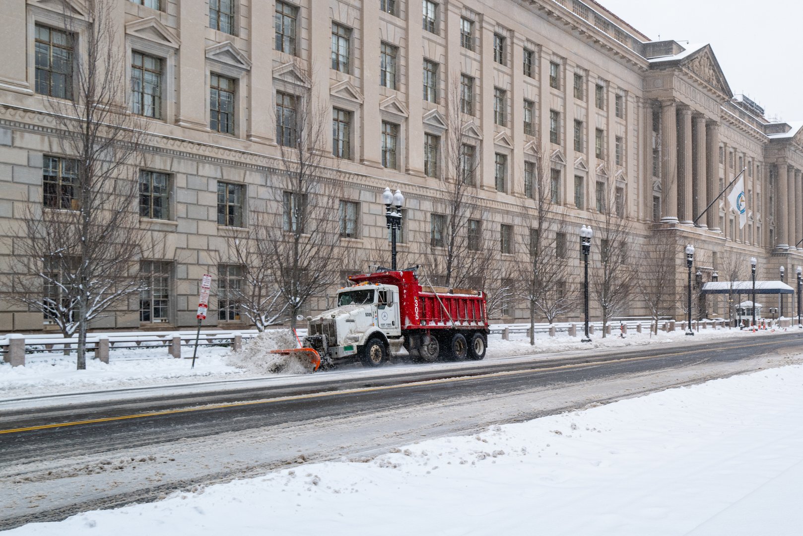 Washington, D.C., U.S.A. - Jan. 6, 2025: A snowplow clears snow in the morning on 15th Street NW in front of the Herbert C. Hoover Building.  It was the city's biggest snowstorm in years.