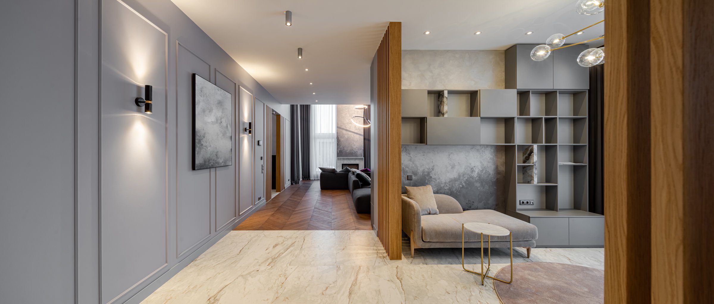 Modern interiro of luxury spacious private house. Grey tones. Wooden design. Cozy sofa. Living room. Shelves and cabinets on wall.