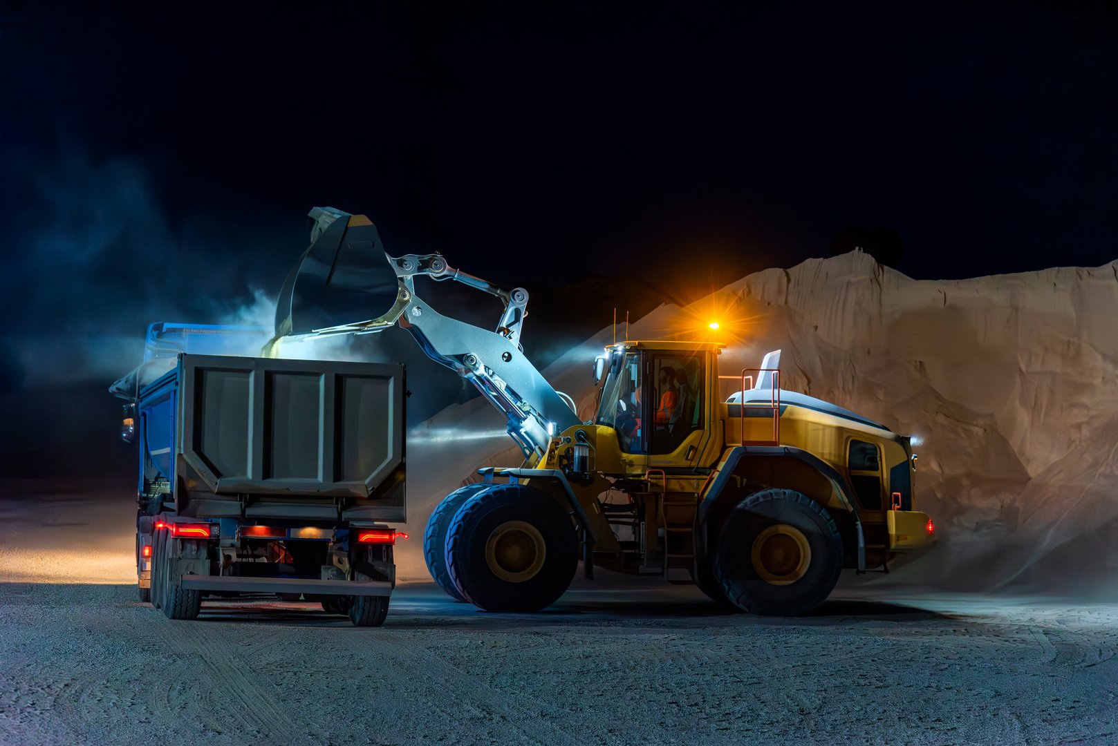 Heavy construction and mining machinery loading a dump truck with gravel in a quarry on the night shift. Close-up.