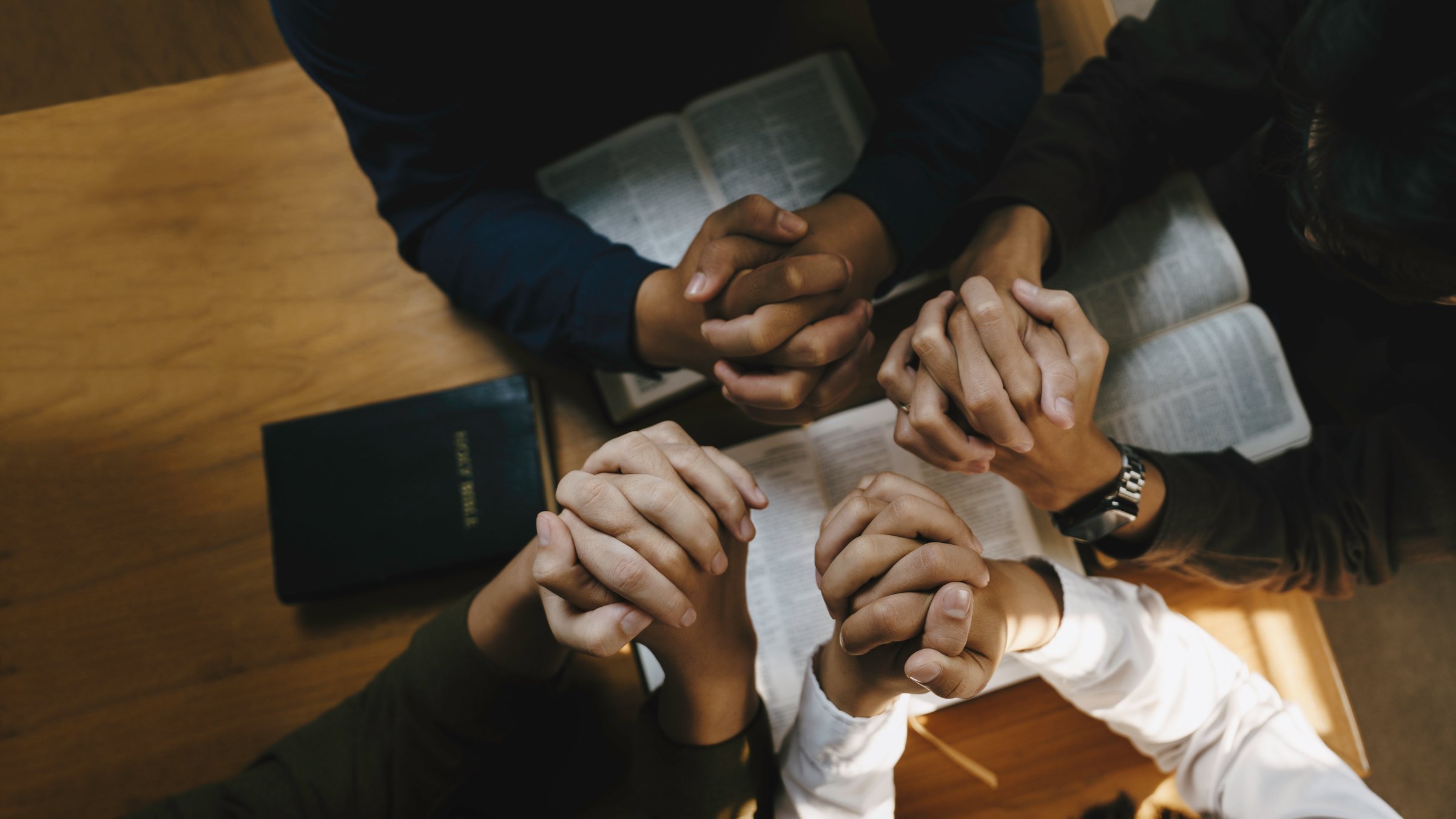 Christian and prayer. Christian group of people holding hands praying worships together to believe and Bible on a wooden table for devotional for prayer meeting concept.