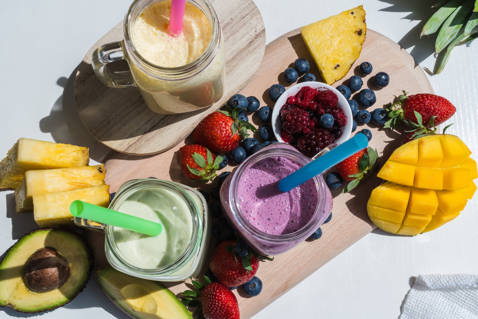 top view of colorful smoothie, healthy detox vitamin diet or vegan food concept, fresh vitamins, breakfast drink with avocado, pineapple, mango, strawberries, blueberries