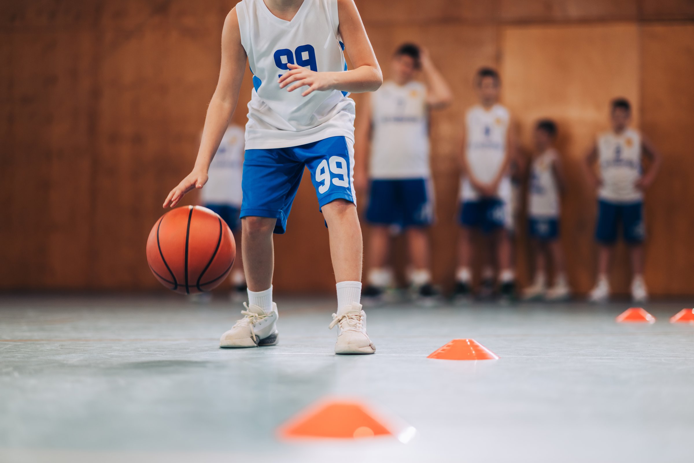 A young basketball player with the ball during a training session, highlighting the essence of youth sport and skill development