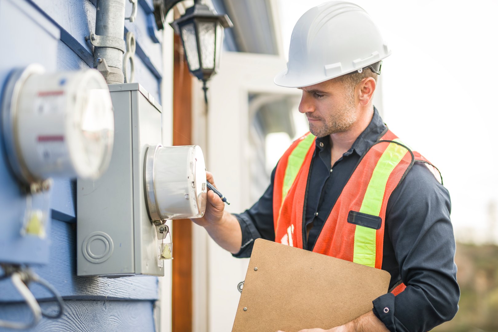 A man with hard hat standing in front of a electric panel
