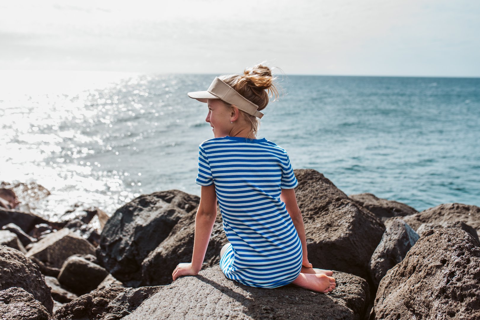 Rear view of beautiful girl by sea in striped dress