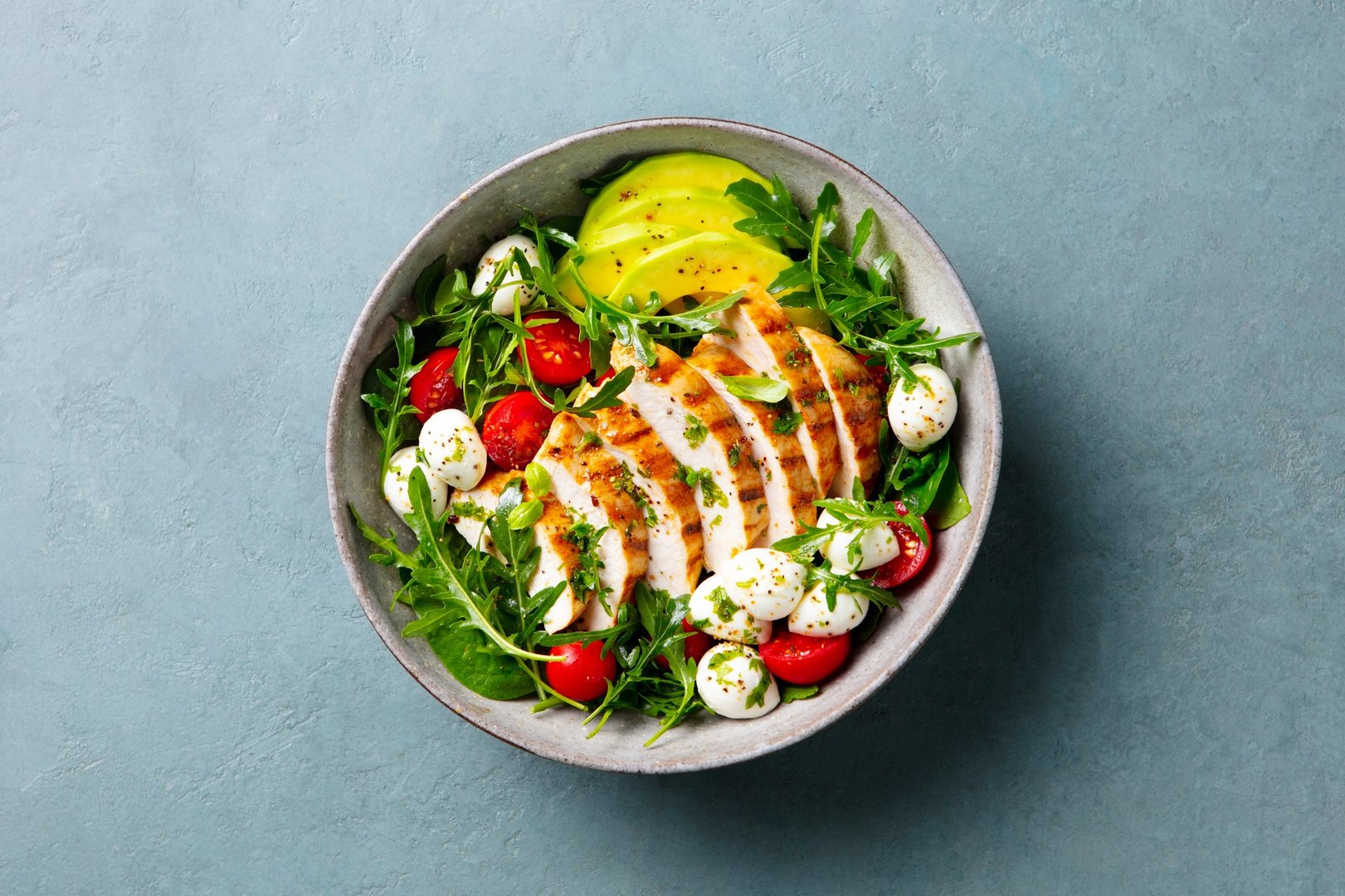 Warm grilled chicken salad with avocado and mozzarella cheese. Close up. Top view.