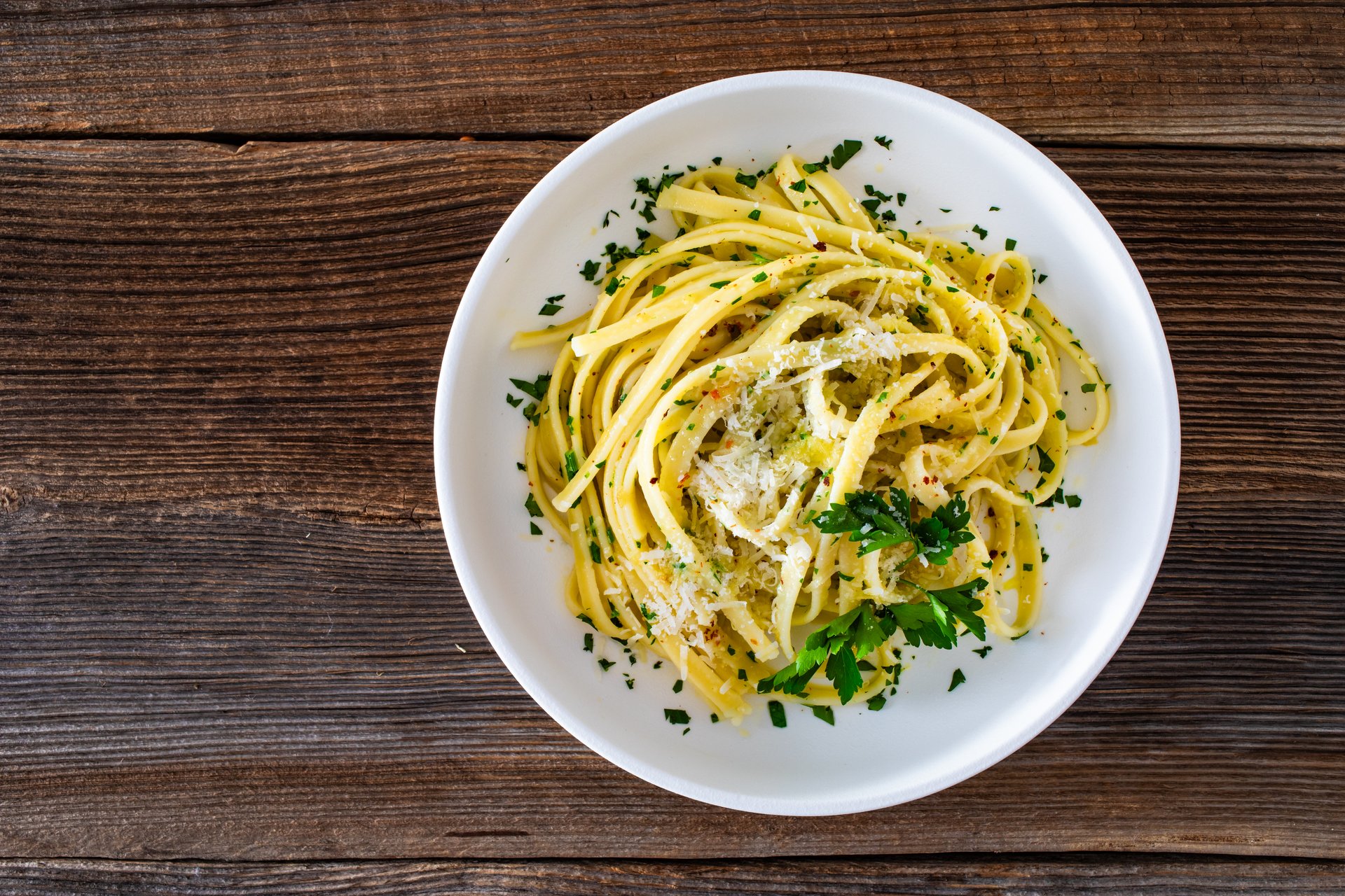 Aglio e olio - pasta with olive oil, parmesan and garlic on wooden table