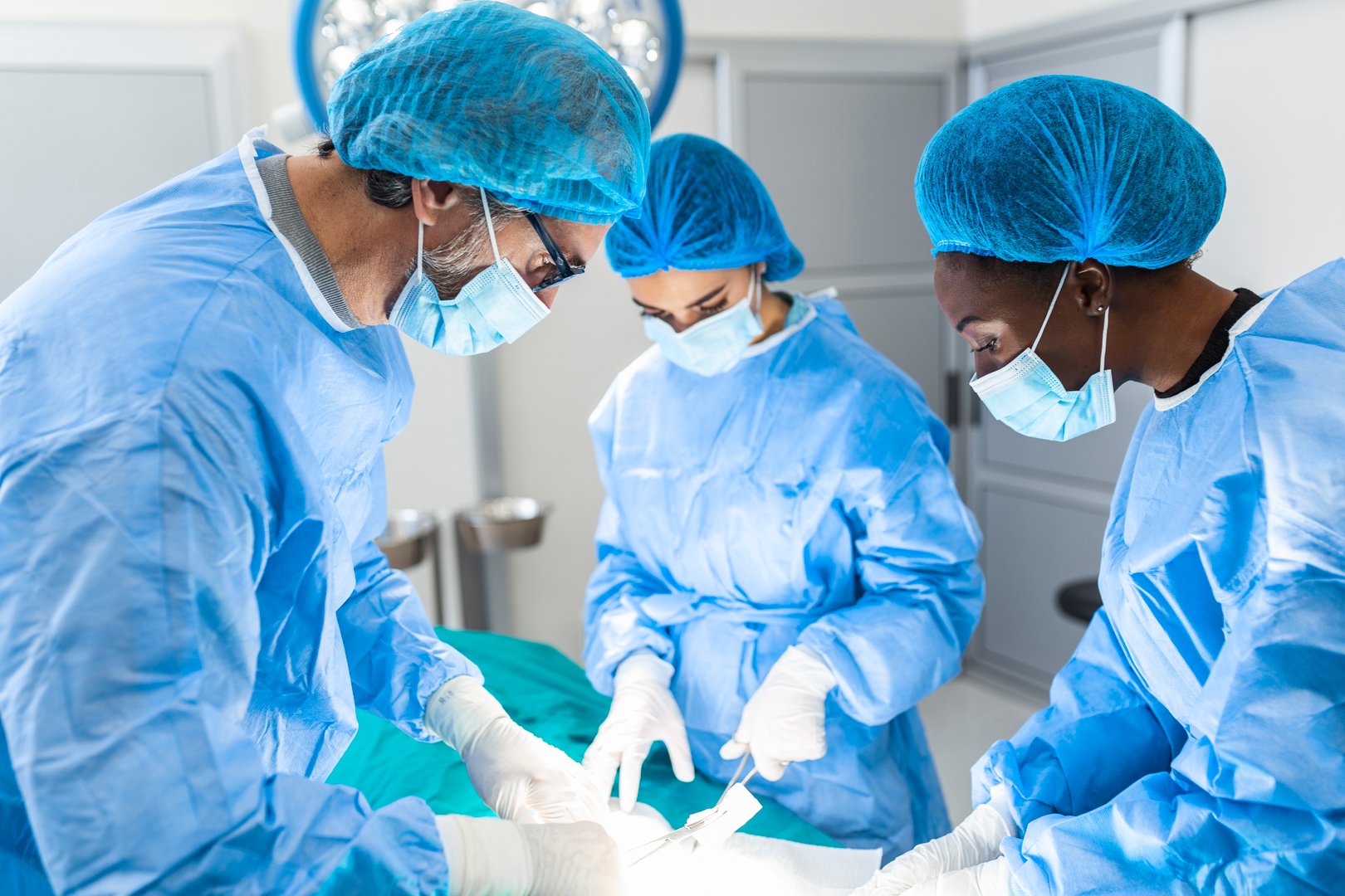 Group of surgeons doing surgery in hospital operating theater. Medical team doing critical operation. Group of surgeons in operating room with surgery equipment. Modern medical background