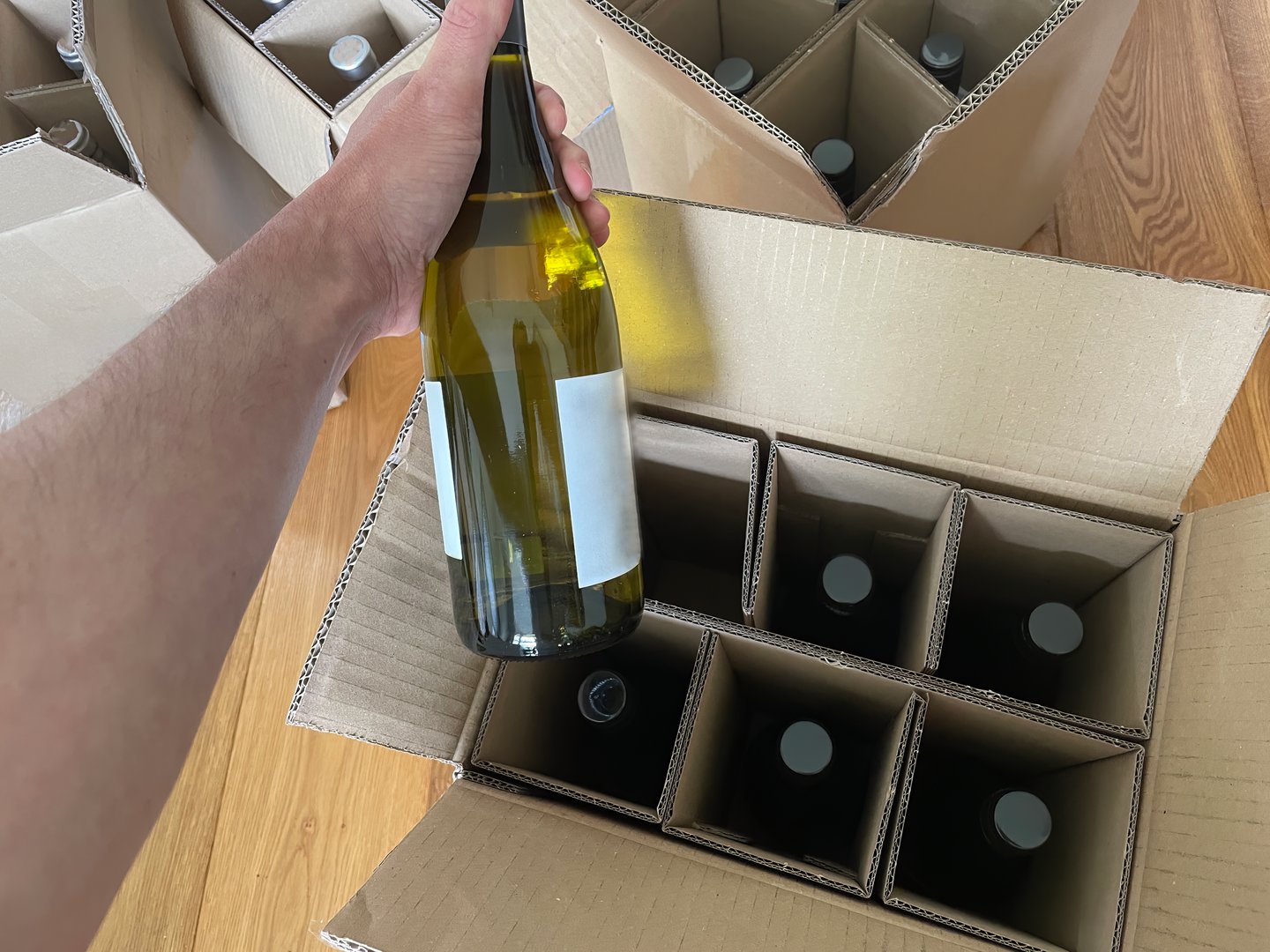 a person is un packing a bottle of wine ordered on the internet out of a delivery box
