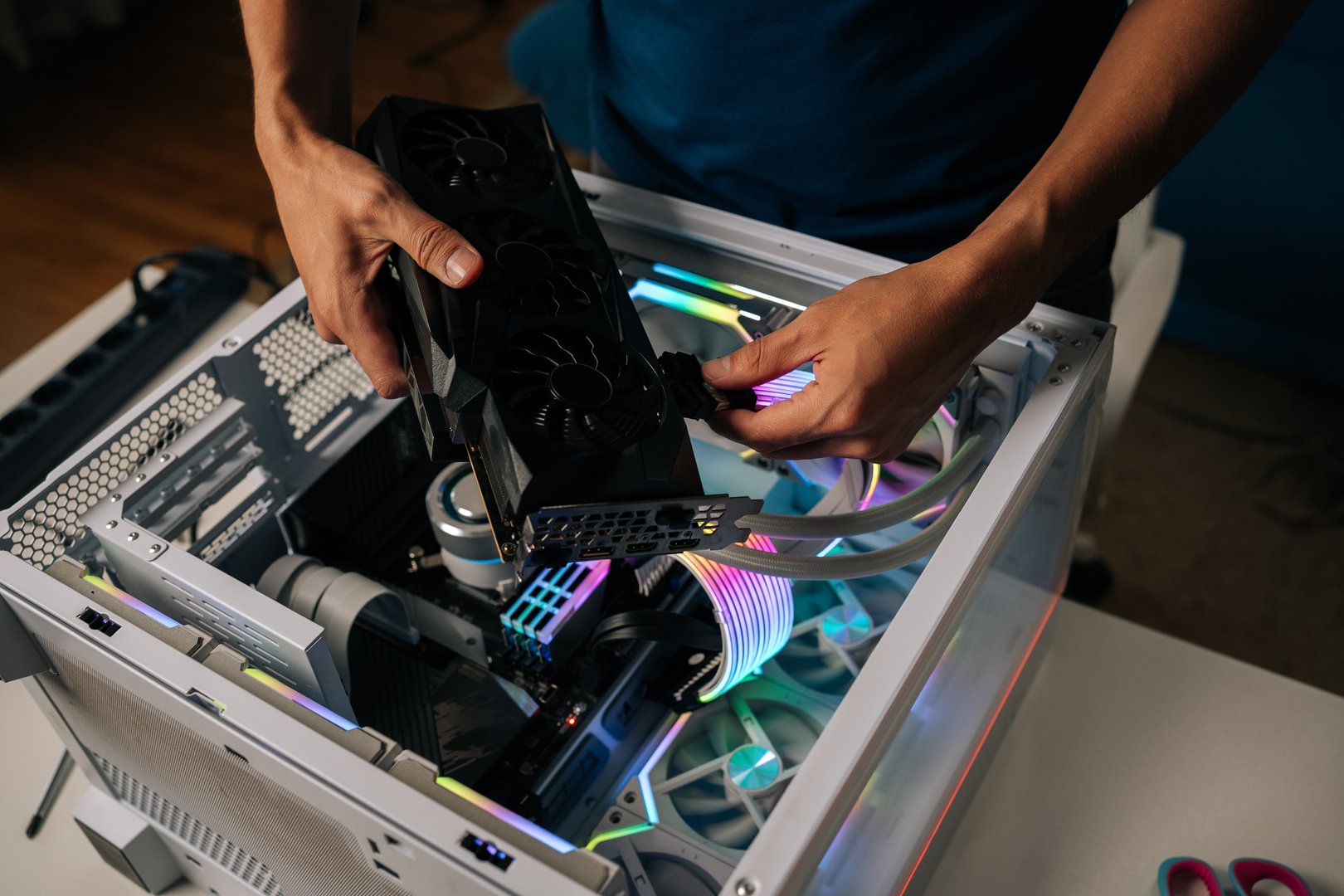 Skilled computer professional inserting high-performance graphics card into custom gaming pc, illuminating interior with vibrant RGB lighting for enhanced visual experience.